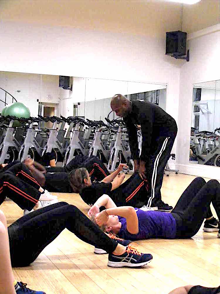 Rob helps a student perform a n excercise routine on the flor at Richmond Olympus Gym
